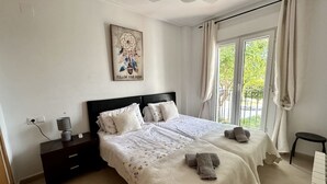 Une chambre avec deux lits, une table de chevet, une lampe et une fenêtre avec des rideaux.