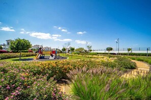 A playground with slides and climbing structures, surrounded by landscaped gardens and a clear sky. - Pool views apartment - AO112LT (La Torre Golf Resort)
