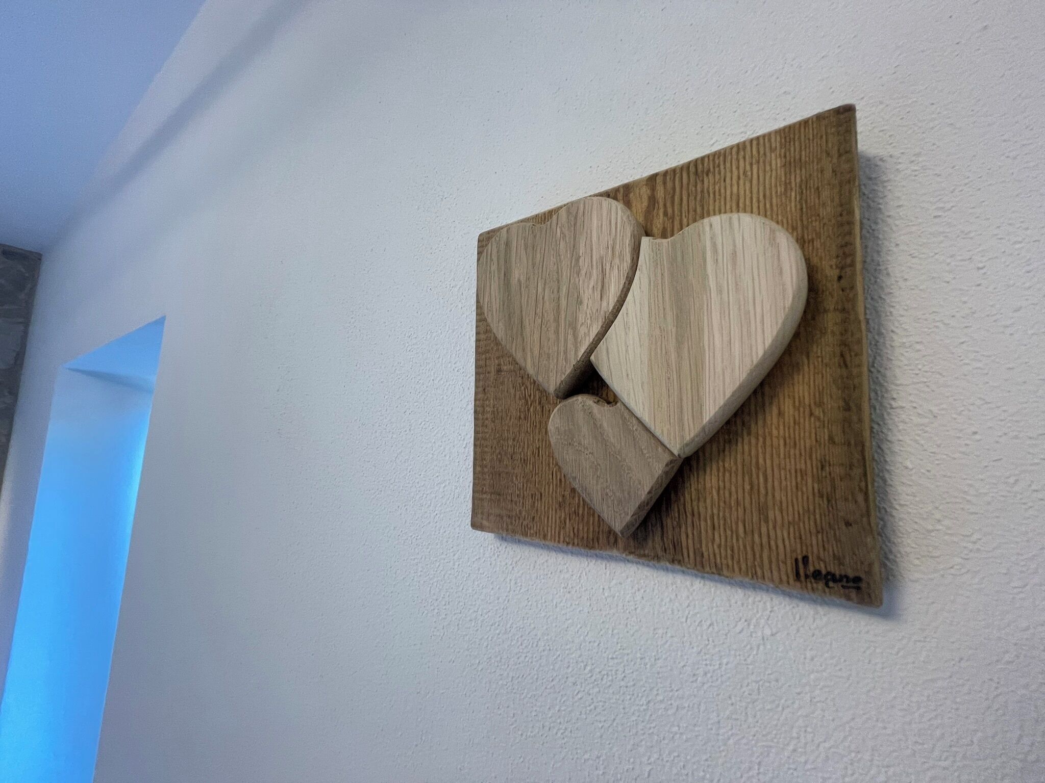 Una decoración con forma de corazón de madera sobre una pared con textura.