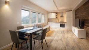 A modern kitchen with a dining area, large windows, and a fireplace. - SnowLake Suite & Apartments (Alleghe)