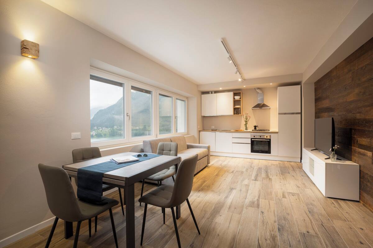 Eine moderne Küche mit Essbereich, großen Fenstern und einem Kamin.