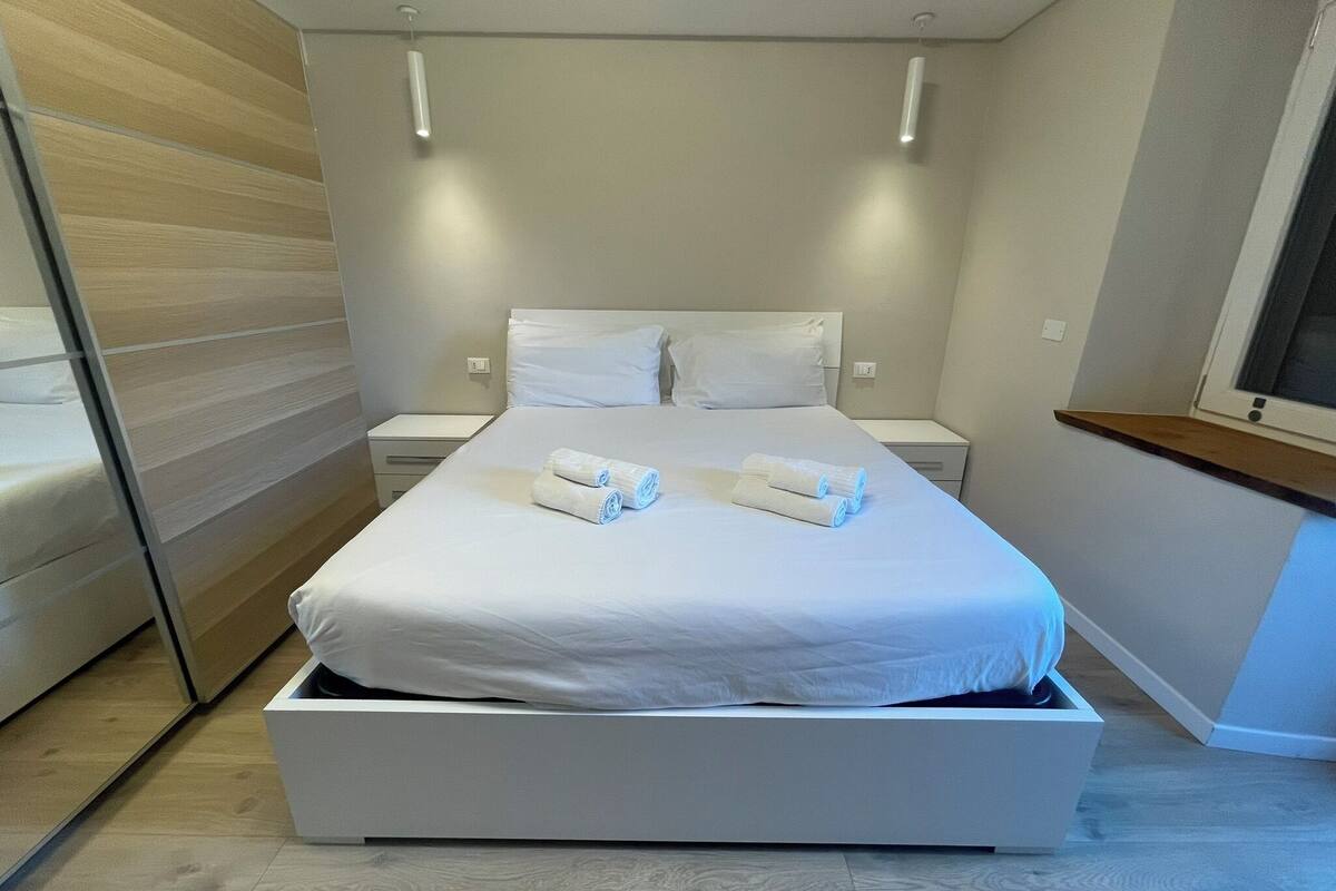Ein modernes Schlafzimmer mit einem großen Bett, zwei Nachttischen und einer eingebauten Bank.