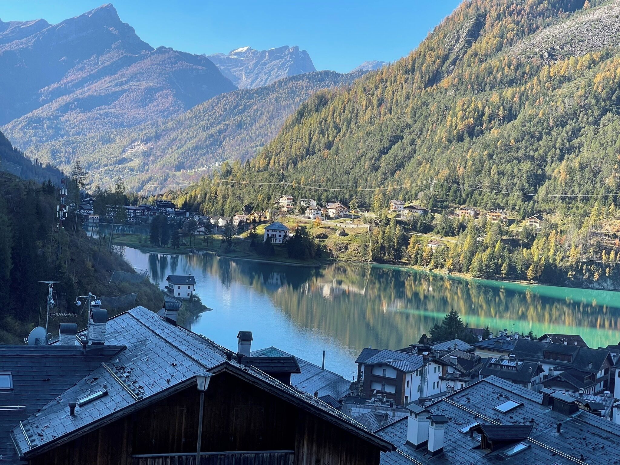 Un pueblo a orillas del lago con casas de madera tradicionales, una vista despejada del lago y montañas al fondo.