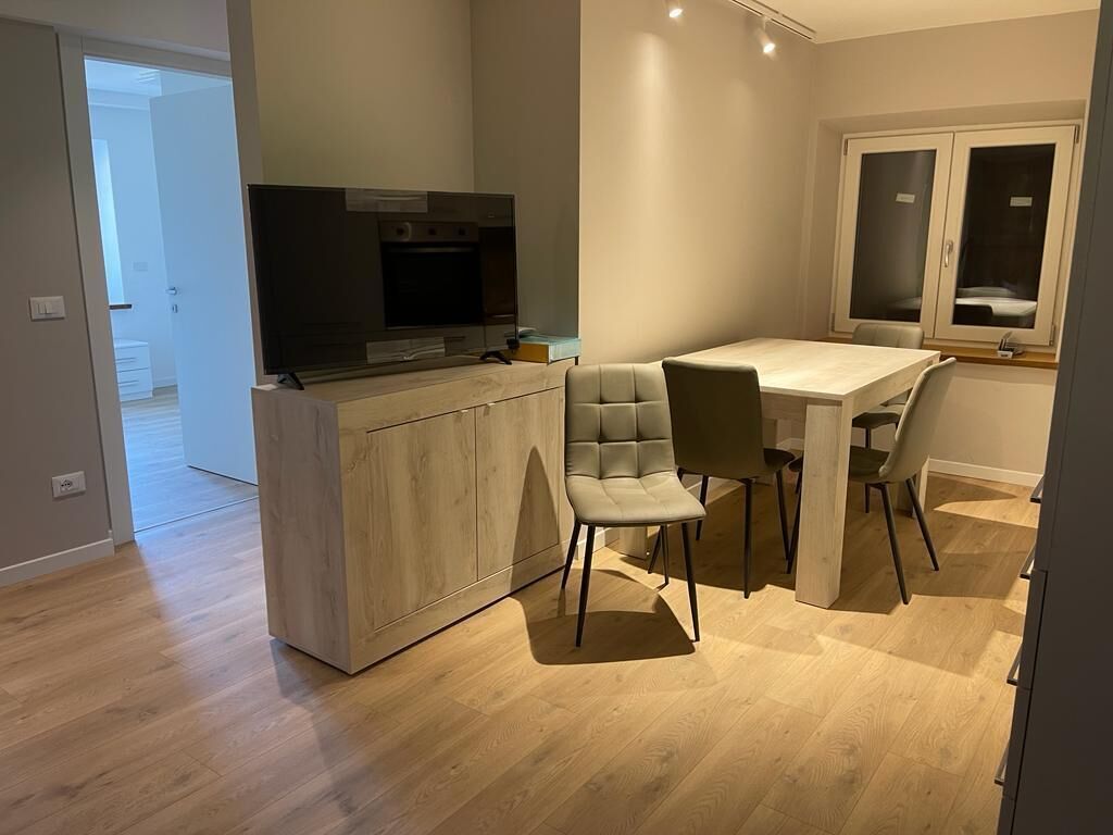 A modern kitchen with a built-in TV, wooden cabinets, and a dining area with two chairs.
