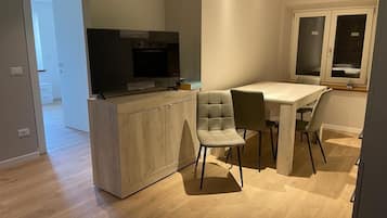 A modern kitchen with a built-in TV, wooden cabinets, and a dining area with two chairs.