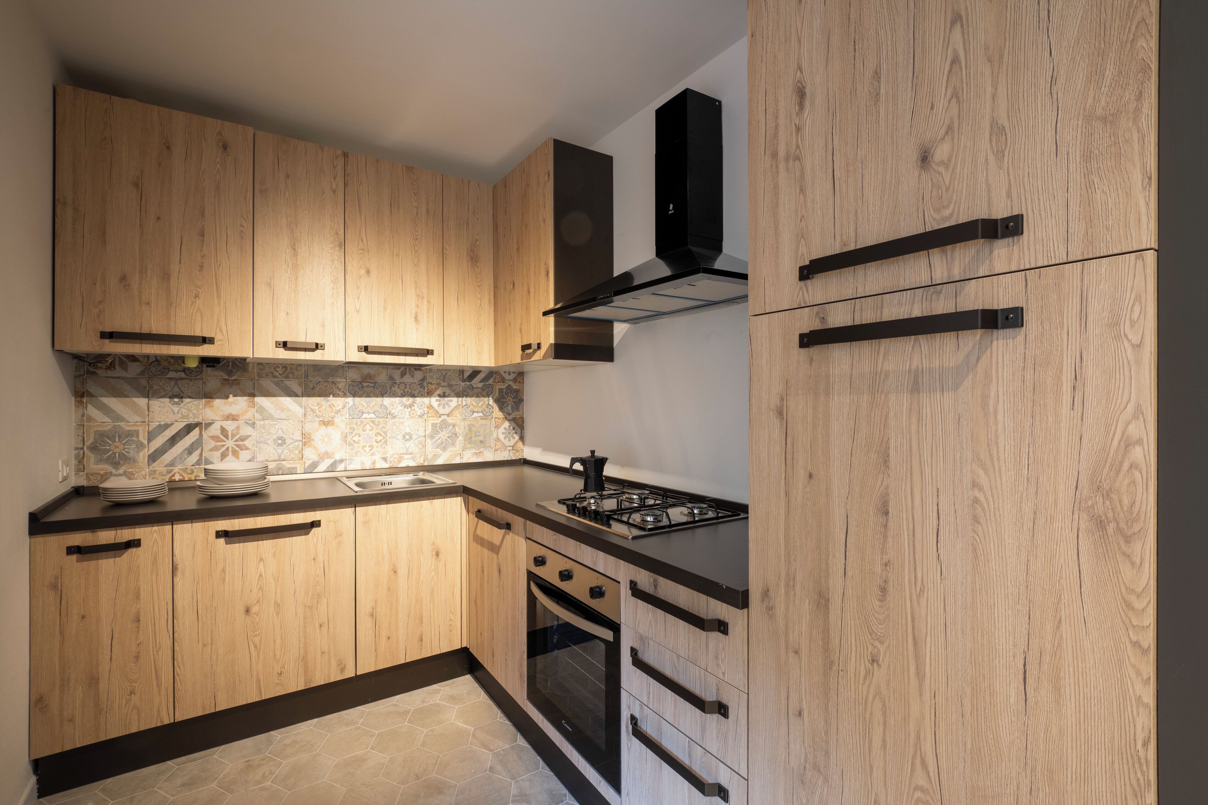 Een keuken met houten kastjes, een gasfornuis en een inbouwoven.