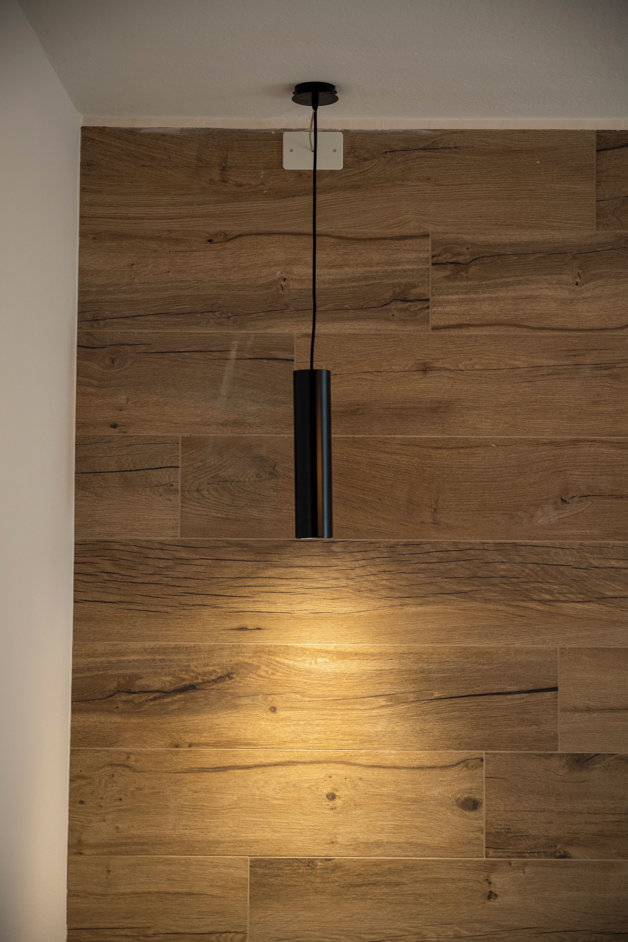 A wooden wall with a modern light fixture.