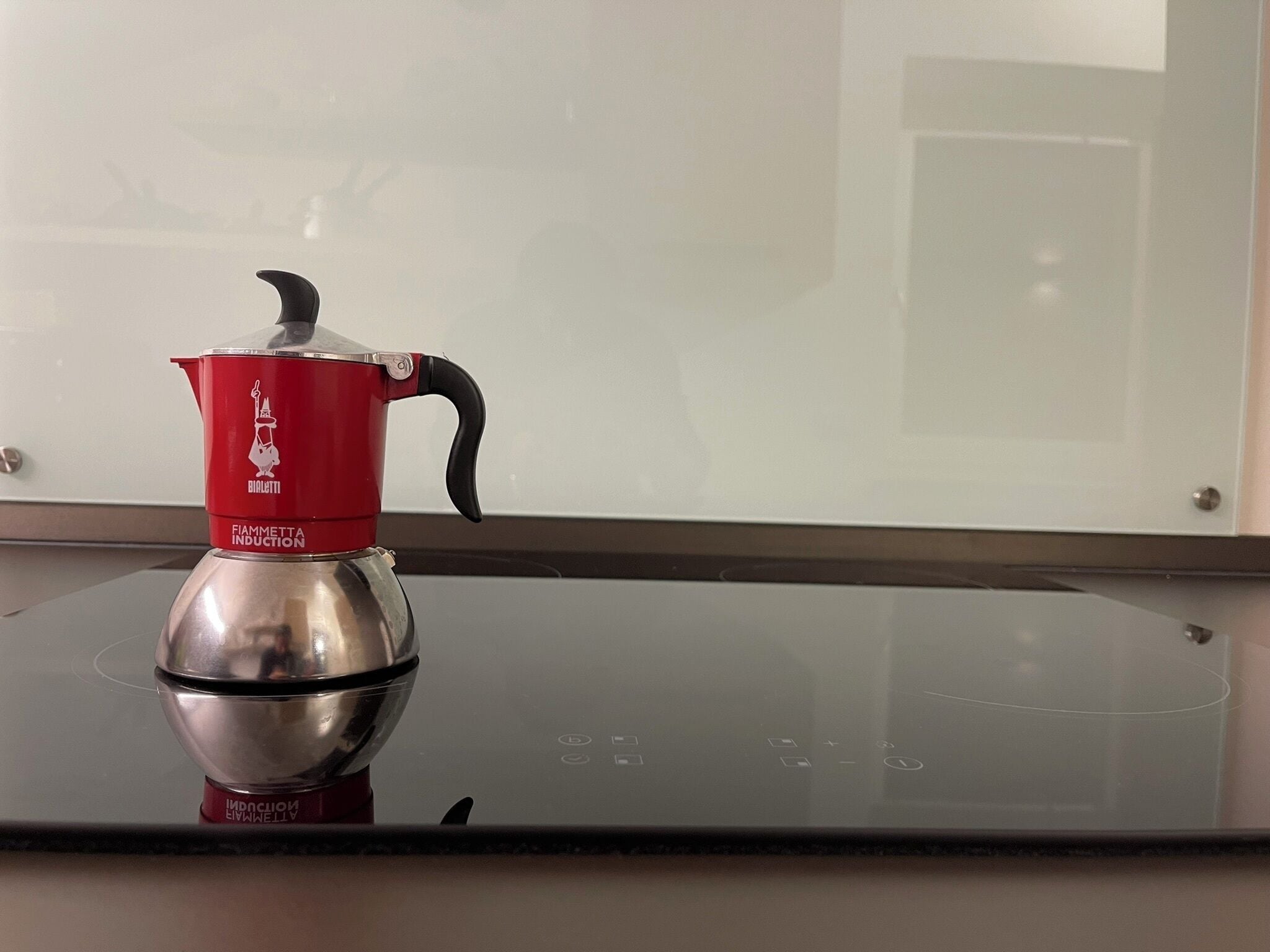 Une plaque de cuisson à induction rouge et argentée, avec une bouilloire dessus.