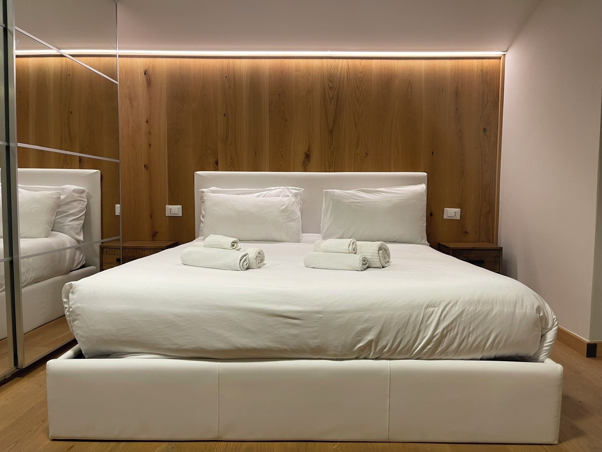 Un dormitorio moderno con una cama grande, dos mesitas de noche y un armario empotrado.
