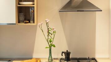 Una cocina con estufa, horno, armarios de madera y un florero con flores.