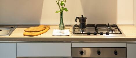 A kitchen with a stove, oven, wooden cabinets, and a vase with flowers.