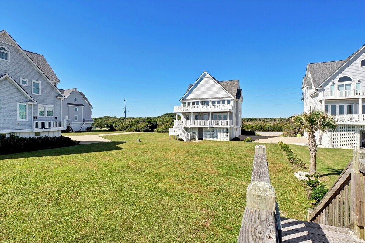 A residential area with three houses, each featuring a balcony and a well-maintained lawn.