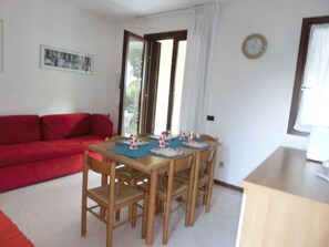 Ein Zimmer mit einer roten Couch, einem Holzespeisetisch mit Tellern und Gläsern sowie einer Uhr an der Wand.