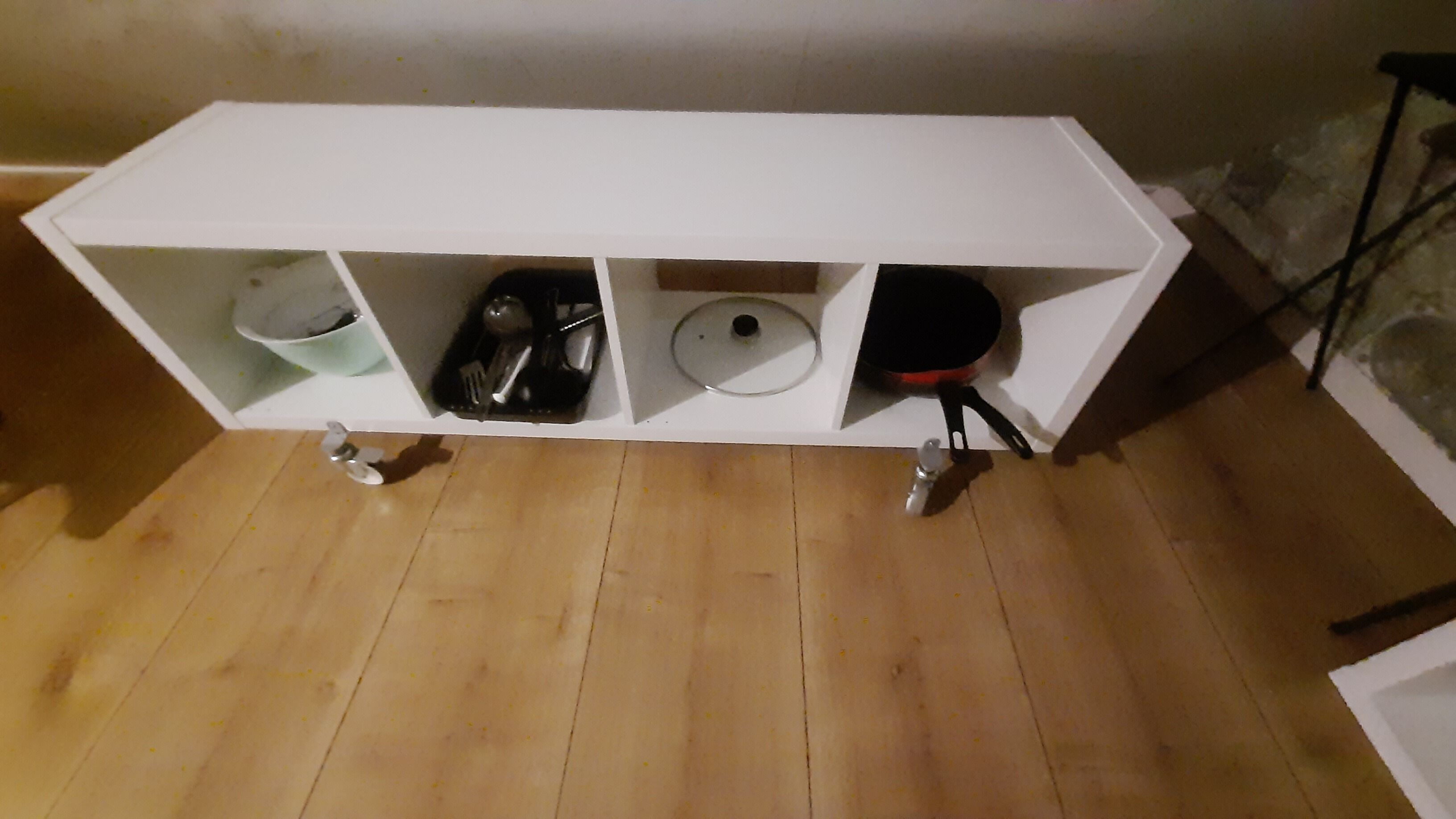 A white kitchen counter with a sink, a dish rack, and a pot.