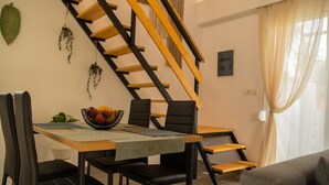 A dining area with a wooden table, black chairs, a fruit bowl, and a staircase with wooden steps. - GK Home II part of Gk Fitness Club (Faliraki)
