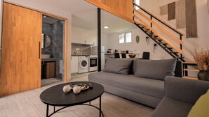 A modern living room with a grey sofa, a black coffee table, and a wooden staircase. - GK Home II part of Gk Fitness Club (Faliraki)