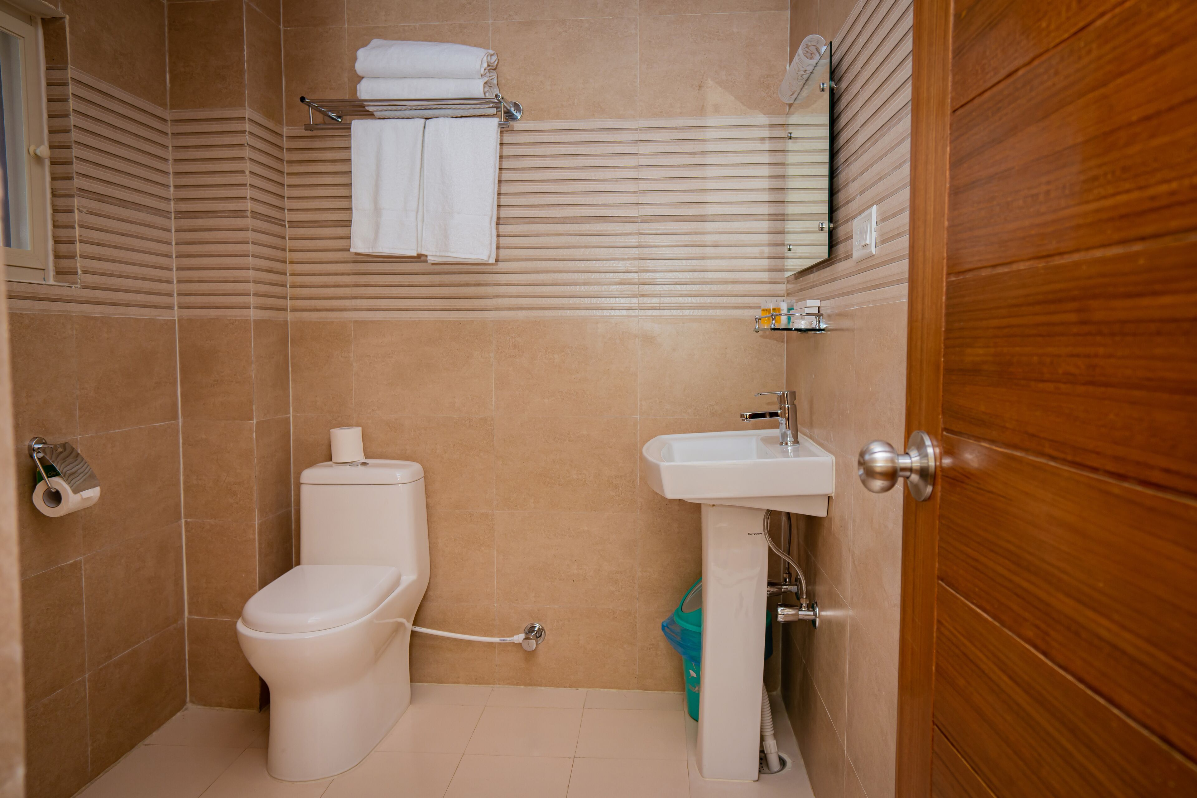 Un baño con inodoro, lavamanos y perchero para toallas.