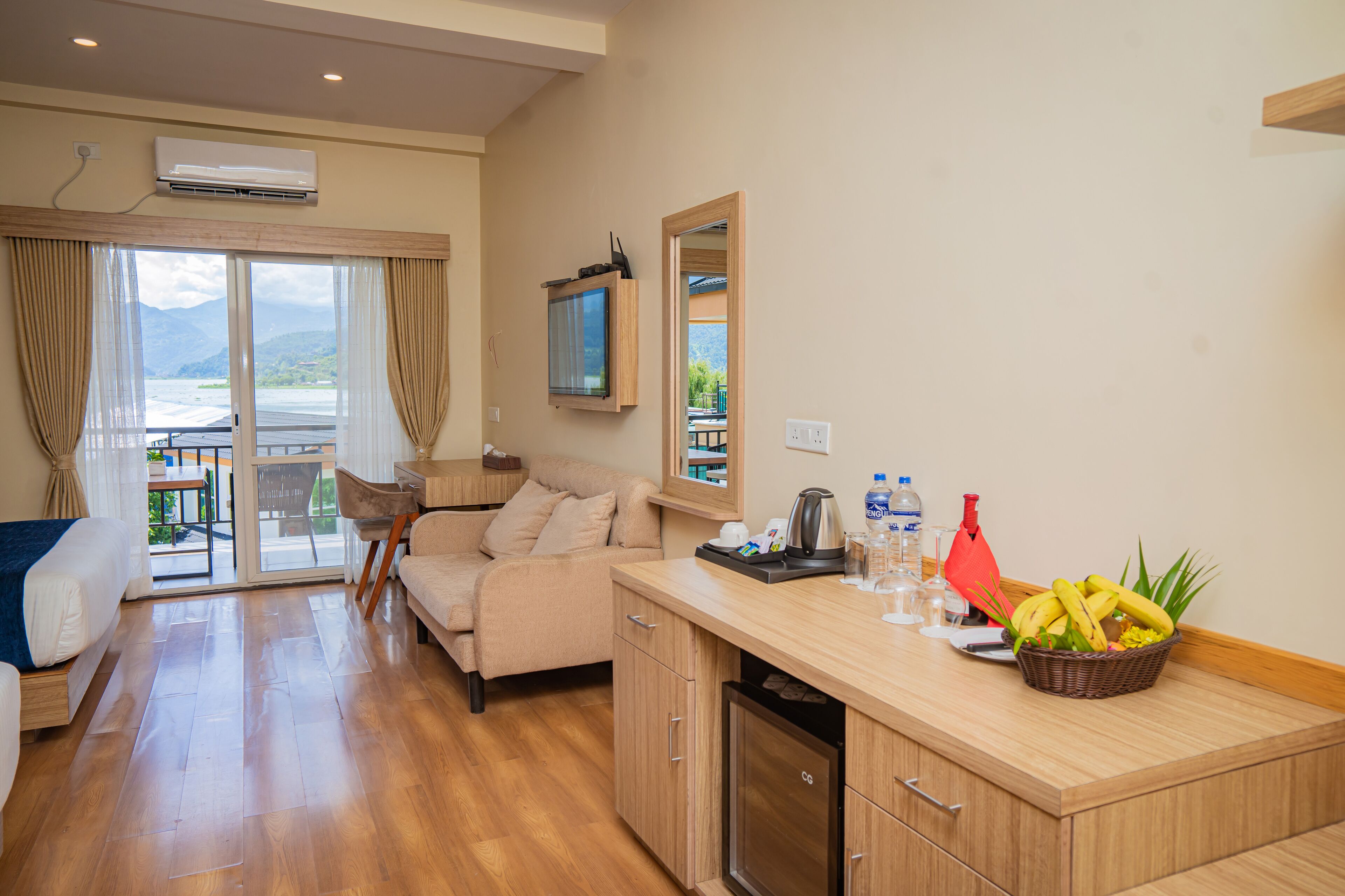 Una habitación de hotel moderna con balcón, sofá, área de cocina con refrigerador y mesa de comedor.