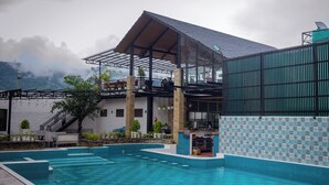 Zona de piscina con área de estar techada y vista a la montaña.