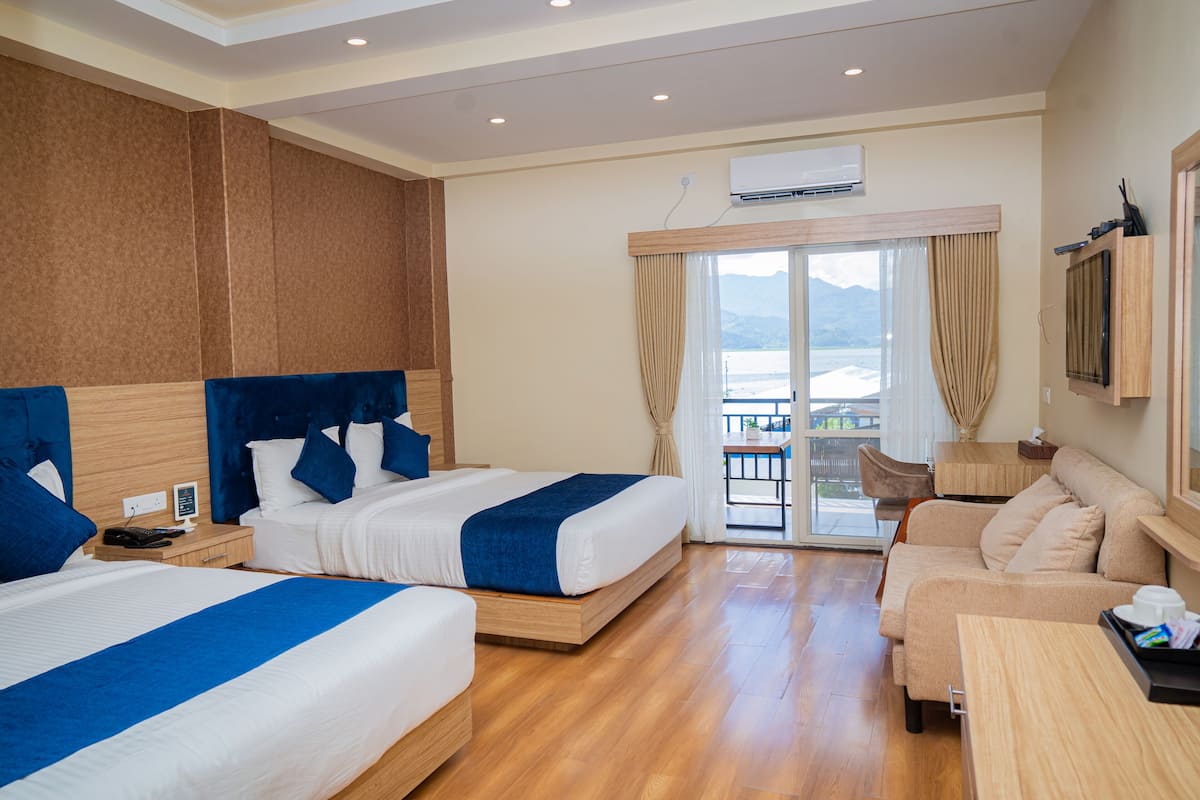 Ein Hotelzimmer mit zwei Betten, einer Couch, einem Balkon mit Blick und einer Klimaanlage.