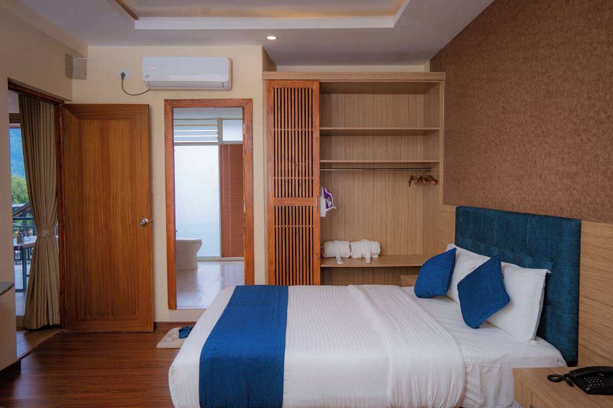 Ein Hotelzimmer mit einem großen Bett, einem Kleiderschrank, einem Badezimmer und Blick ins Freie.