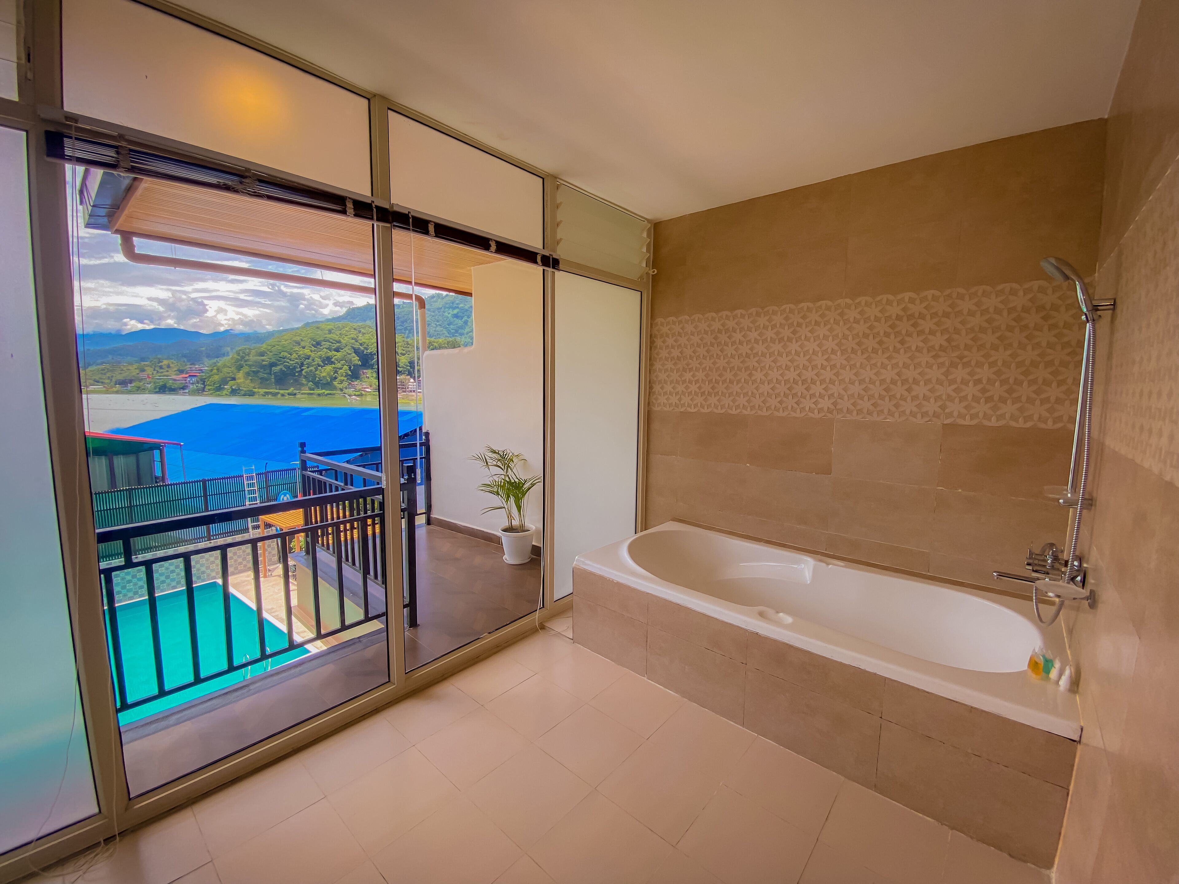 Ein modernes Badezimmer mit Badewanne und Dusche, ein Balkon mit Seeblick und Bergblick sowie ein Blumentopf.
