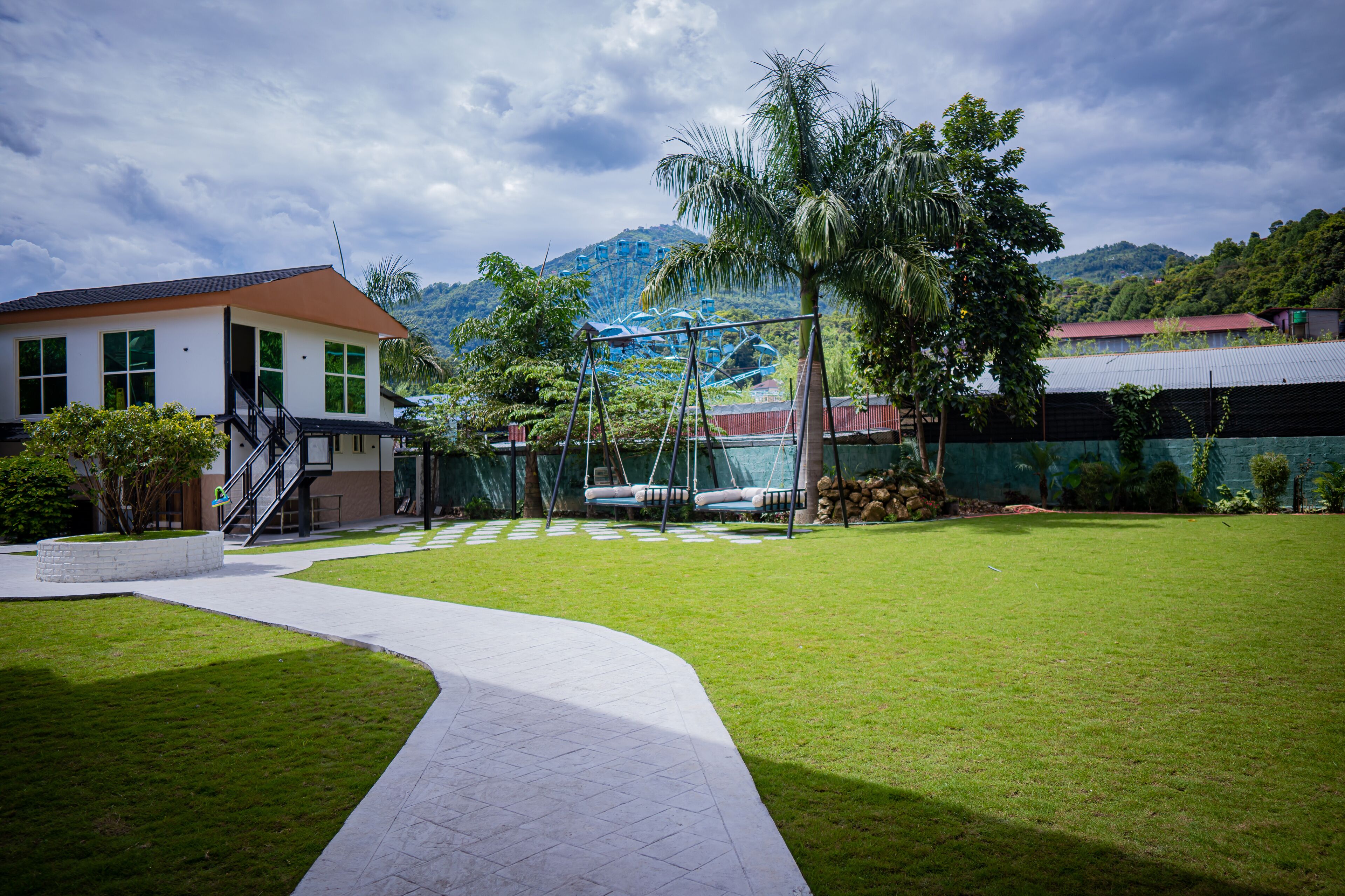 A well-maintained grassy area with a pathway leading to a building with a red roof and white walls.