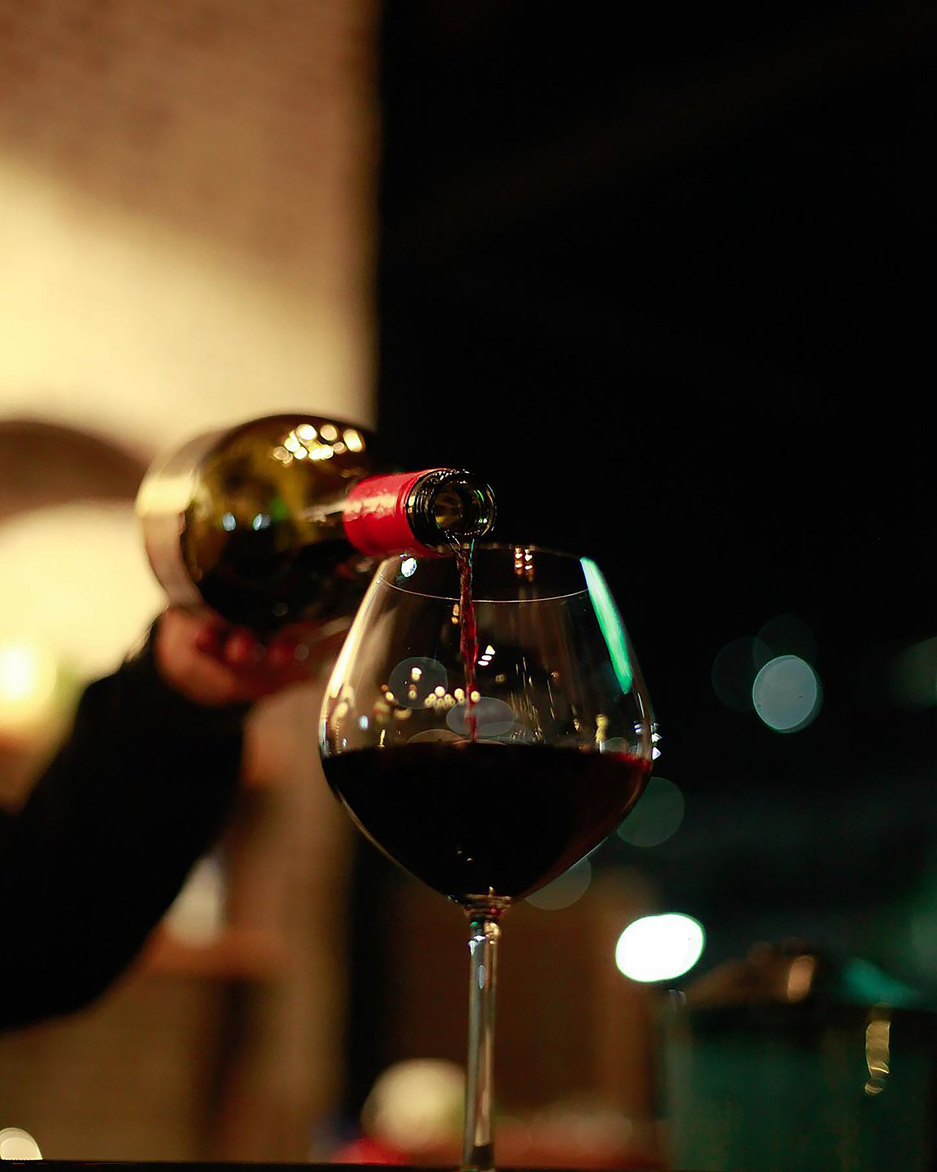 A close-up of a wine glass being filled with red wine.