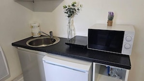 A compact kitchenette with a sink, a microwave, and a small refrigerator. - Skyline King Studio Room 201 (Swansea)