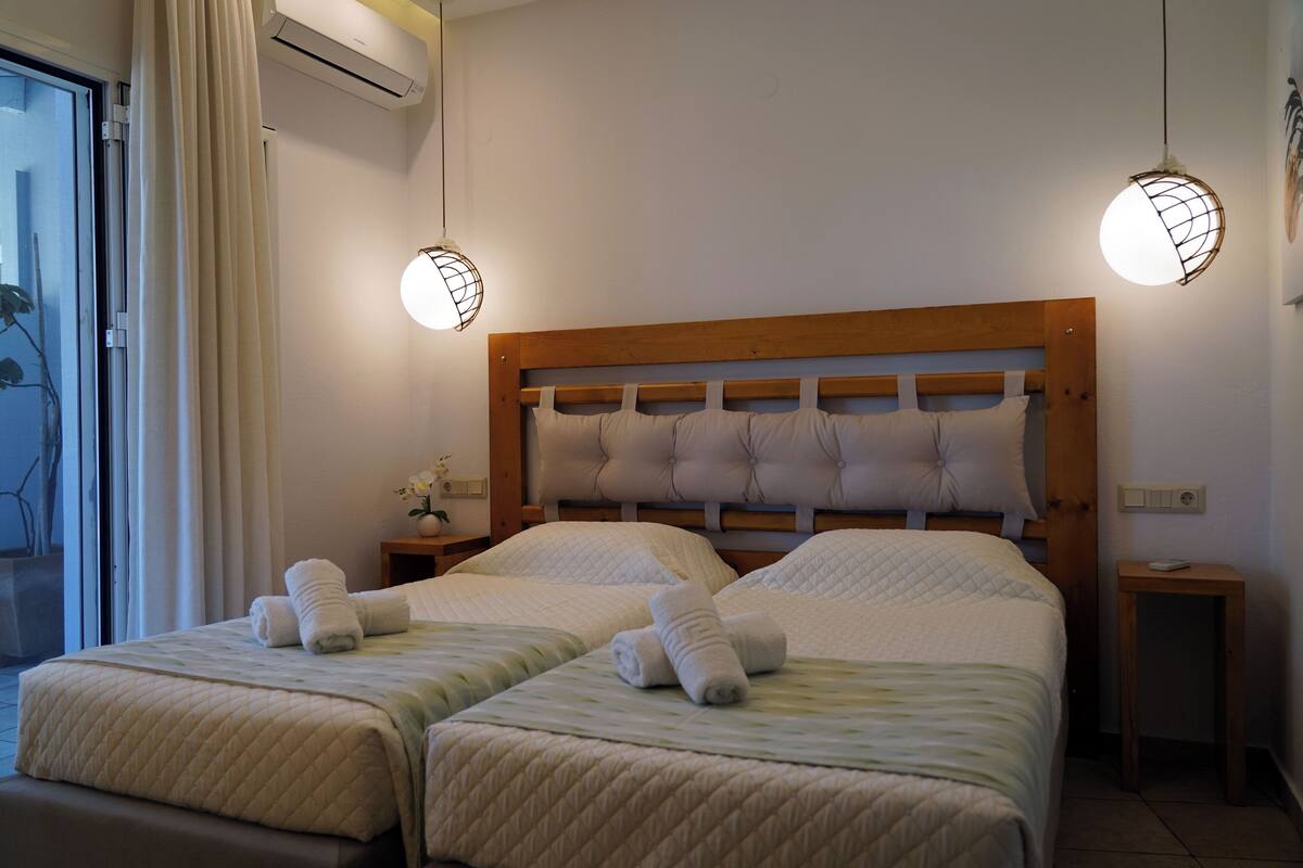 A double bed with a wooden headboard, two bedside tables, and a window with curtains.