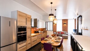 A modern kitchen with stainless steel appliances, wooden cabinets, and a dining area with a table set for four.