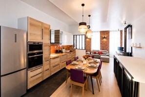 Eine moderne Küche mit Edelstahlgeräten, Holzschränken und einem Essbereich mit Tisch für vier Personen.