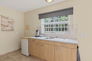Cocina compacta con lavavajillas integrado, cafetera y ventana con vistas a zonas verdes.