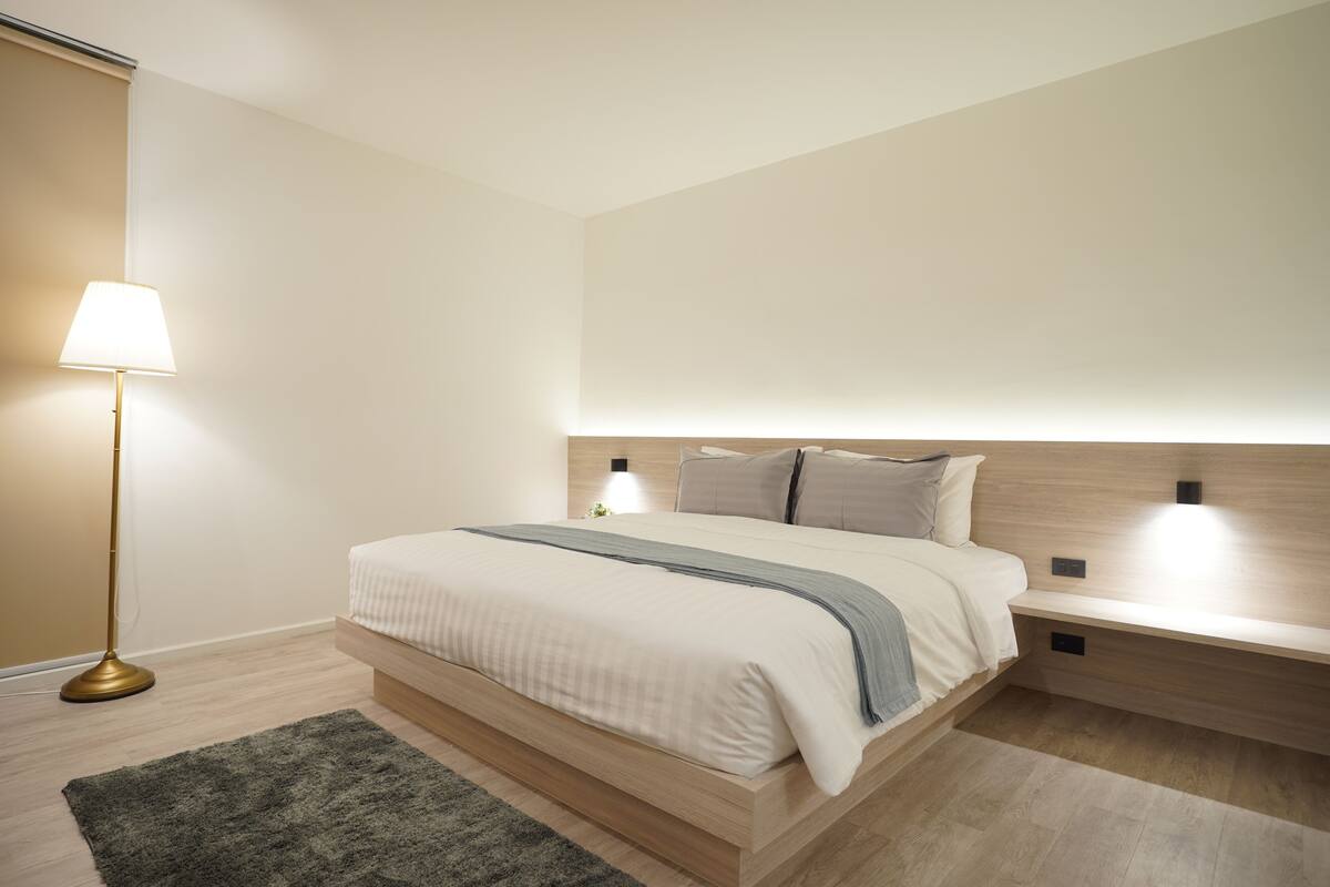 A modern bedroom with a bed, bedside tables, a floor lamp, and a rug.