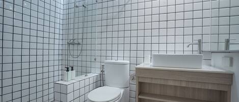 Un baño moderno con azulejos blancos, un inodoro, un lavabo y una ducha.