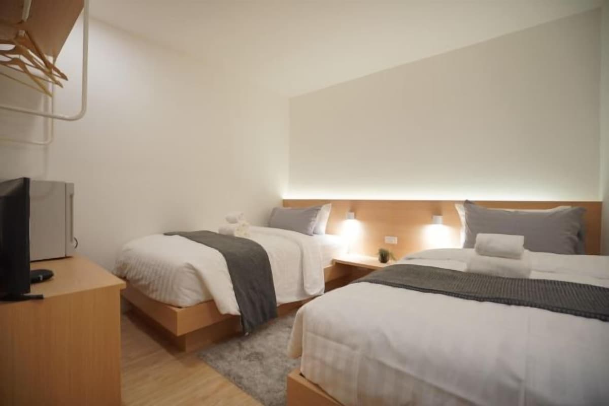 A hotel room with two beds, a TV, and a desk.