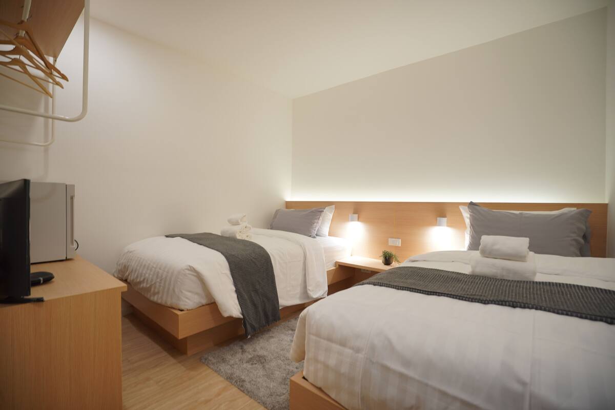 A hotel room with two beds, a TV, and a desk.