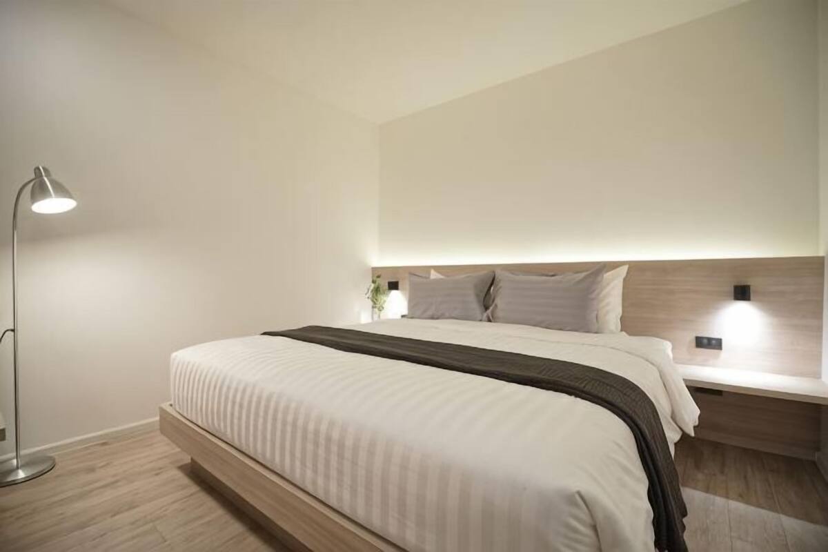 A modern bedroom with a bed, bedside lamps, and a nightstand.