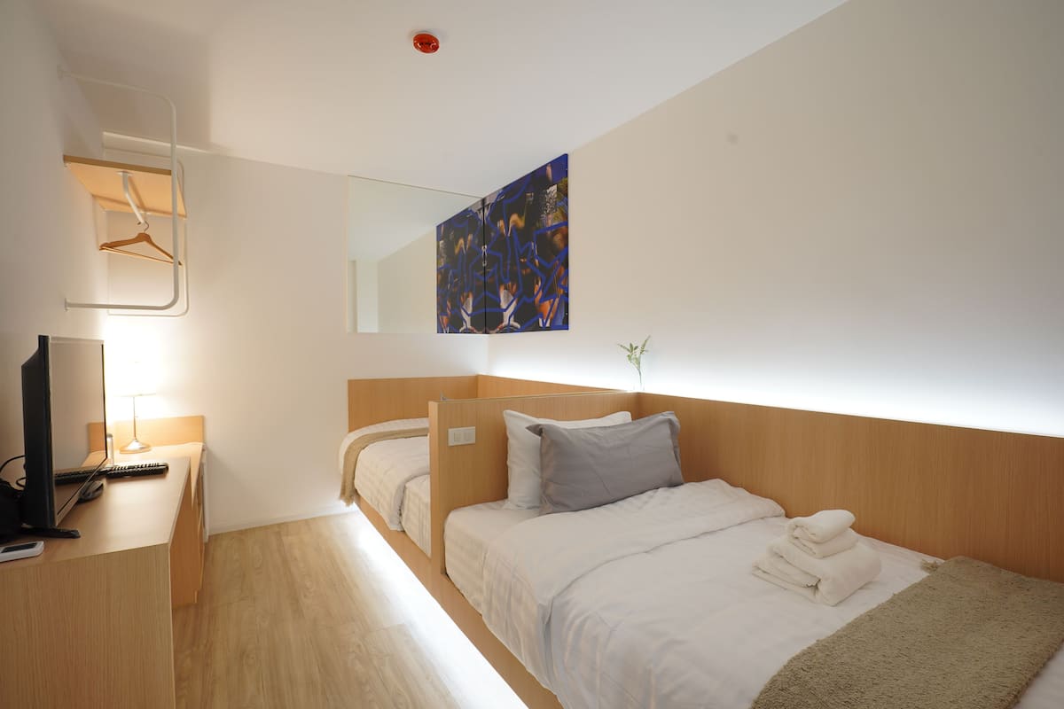 A hotel room with a bed, a desk with a computer, and a painting on the wall.