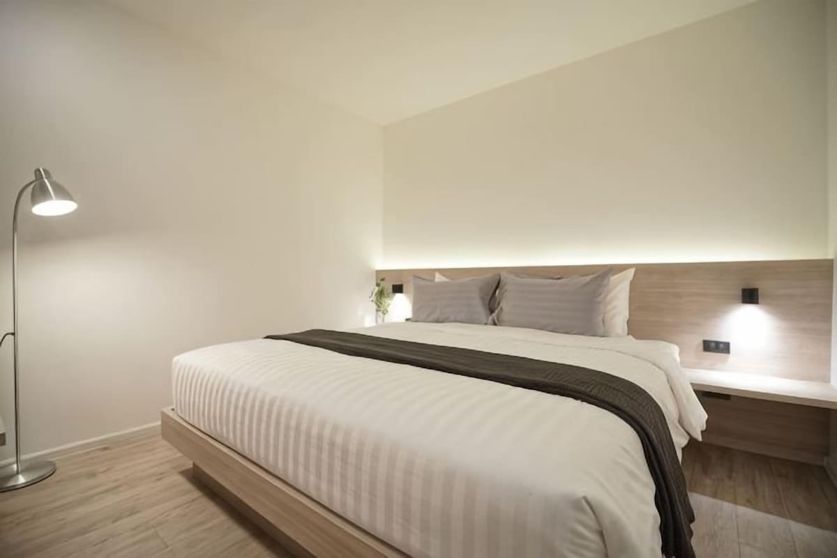 A modern bedroom with a bed, bedside lamps, and a nightstand.