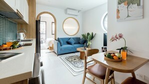 A modern kitchen with a blue sofa, dining table with fruit, and a large mirror. - Crescendo Boutique Studio  (Hanoi)