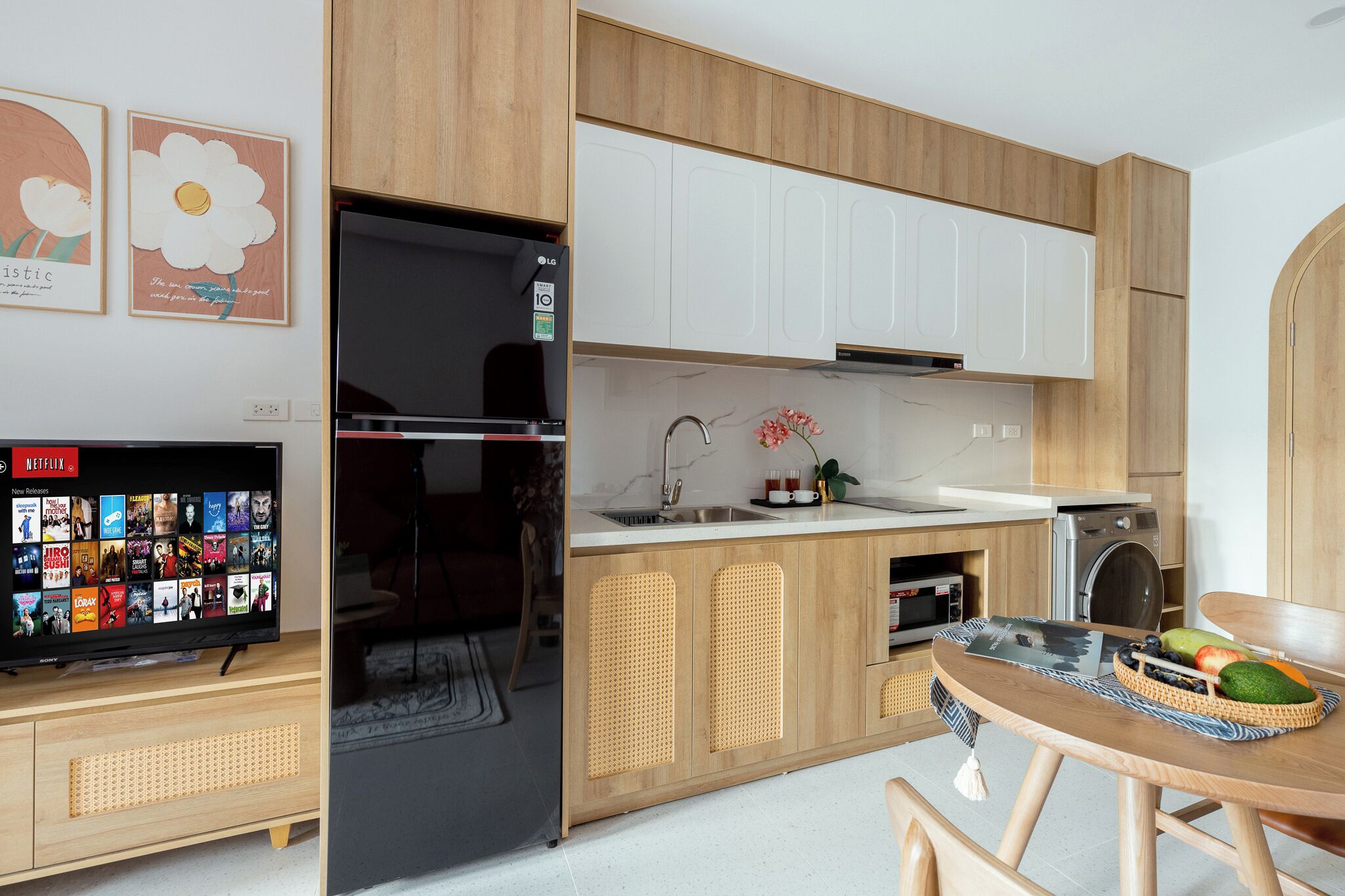 Una cocina moderna con armarios de madera, refrigerador empotrado, un lavamanos y un comedor con mesa.