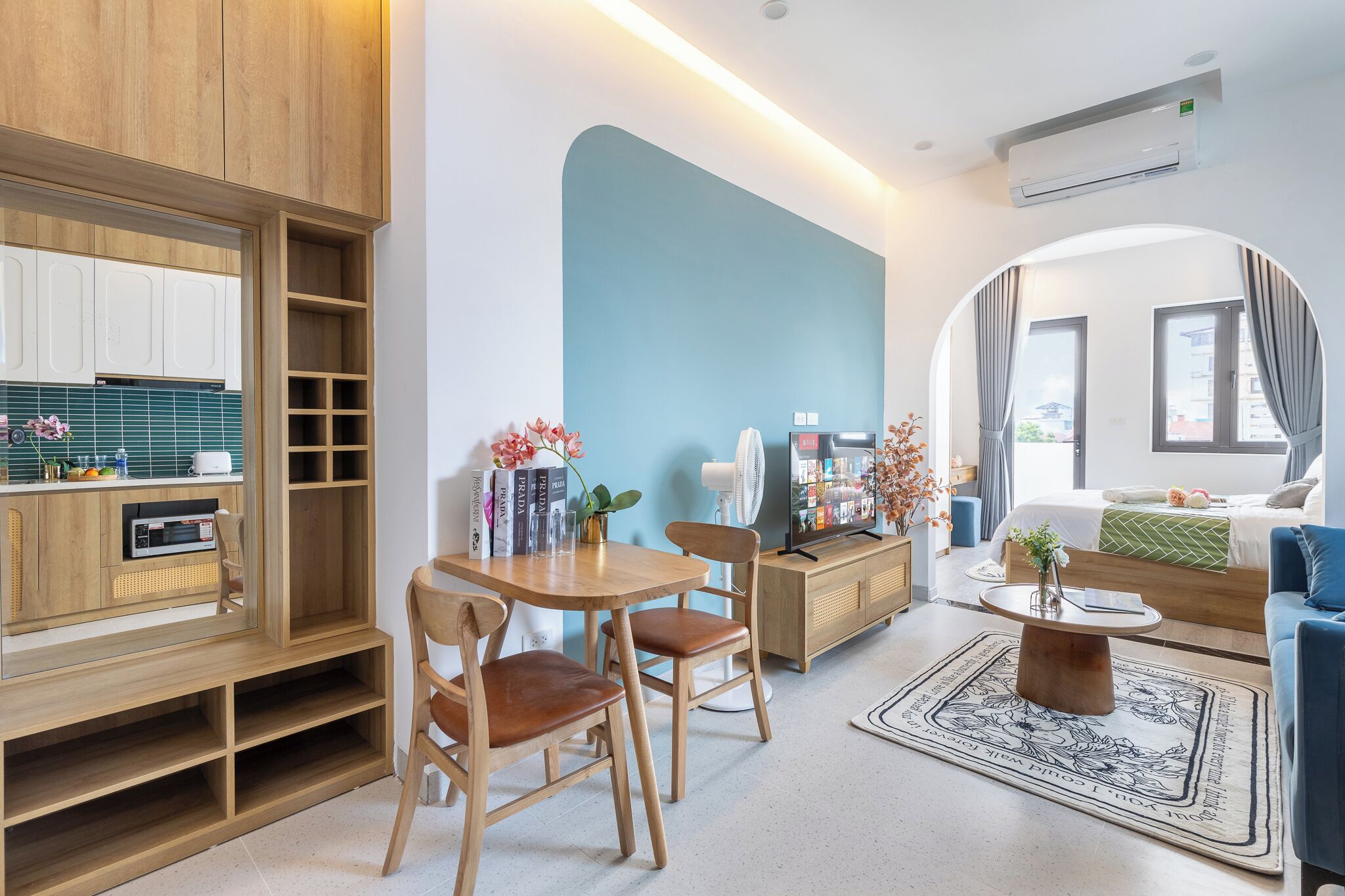 A modern living room with a dining area, kitchen, and a large window.