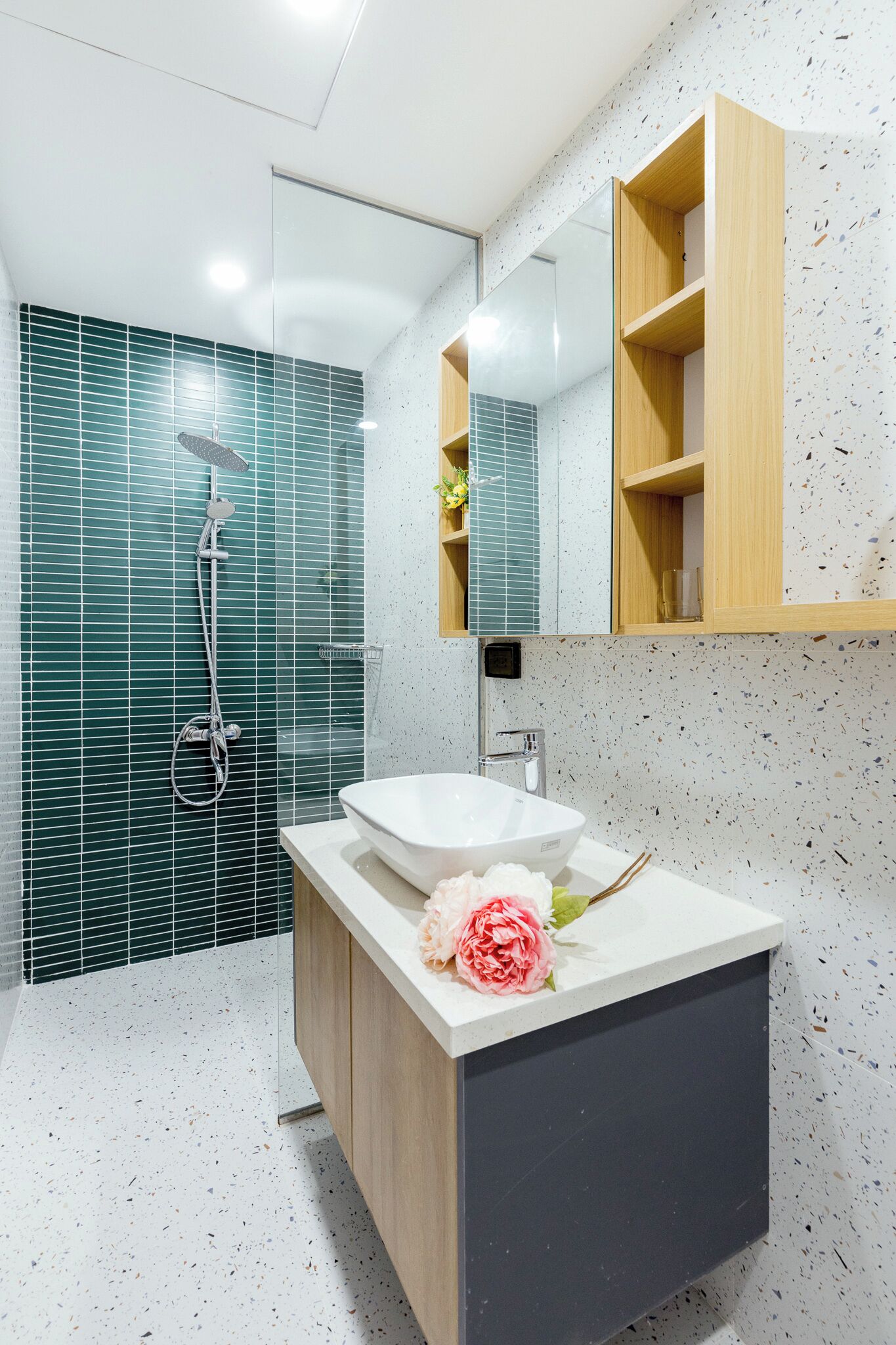 A modern bathroom with a freestanding sink, a shower with a glass door, and a wooden vanity with a mirror above.