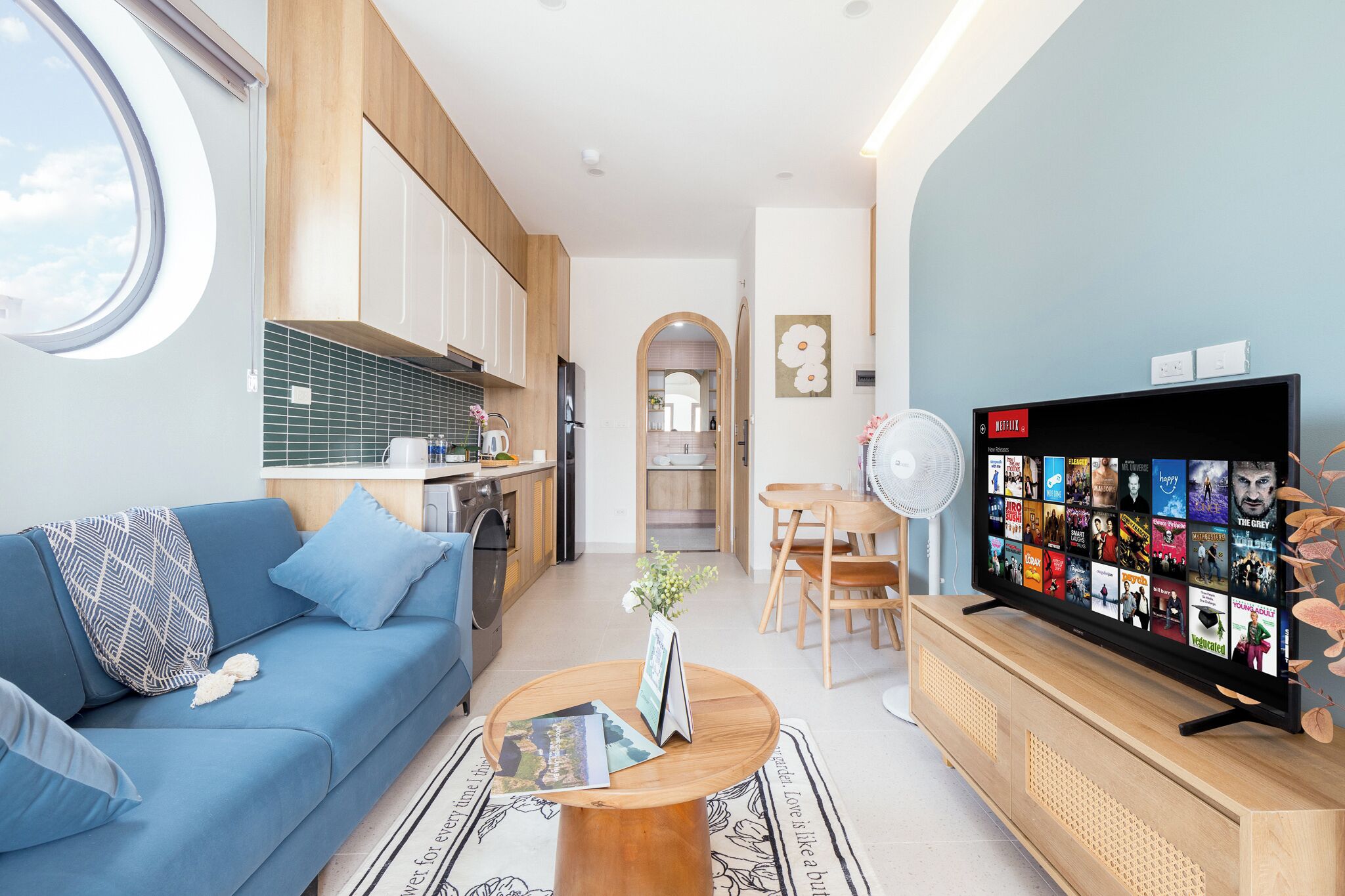 A modern living room with a blue sofa, a coffee table, and a TV displaying a movie selection.