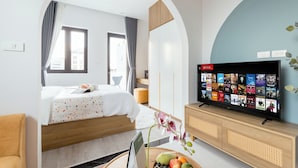 A hotel room with a bed, a TV displaying movie options, a wooden cabinet, and a window with curtains. - Crescendo Boutique Studio  (Hanoi)