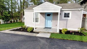Une maison de plain-pied avec une porte d’entrée bleu clair, un petit porche et une pelouse bien entretenue.