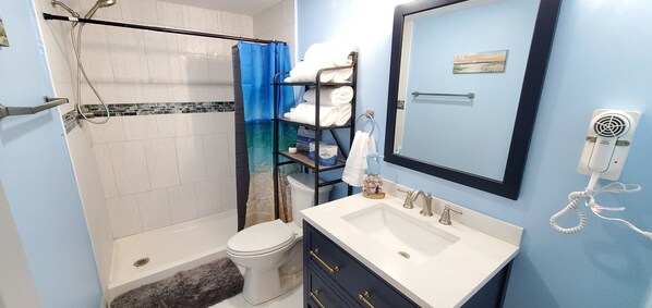 A bathroom with a shower, toilet, sink, and a towel rack with towels. - 2 Bedroom Home Located in Lewes (Lewes)