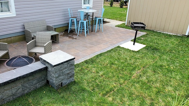 Un espace patio aménagé avec du mobilier d’extérieur, un foyer en pierre et un barbecue.