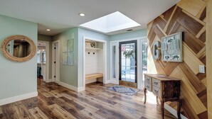 Un hall d’entrée spacieux, doté d’une verrière, d’un plancher en bois et d’un mur orné d’un motif en chevrons.